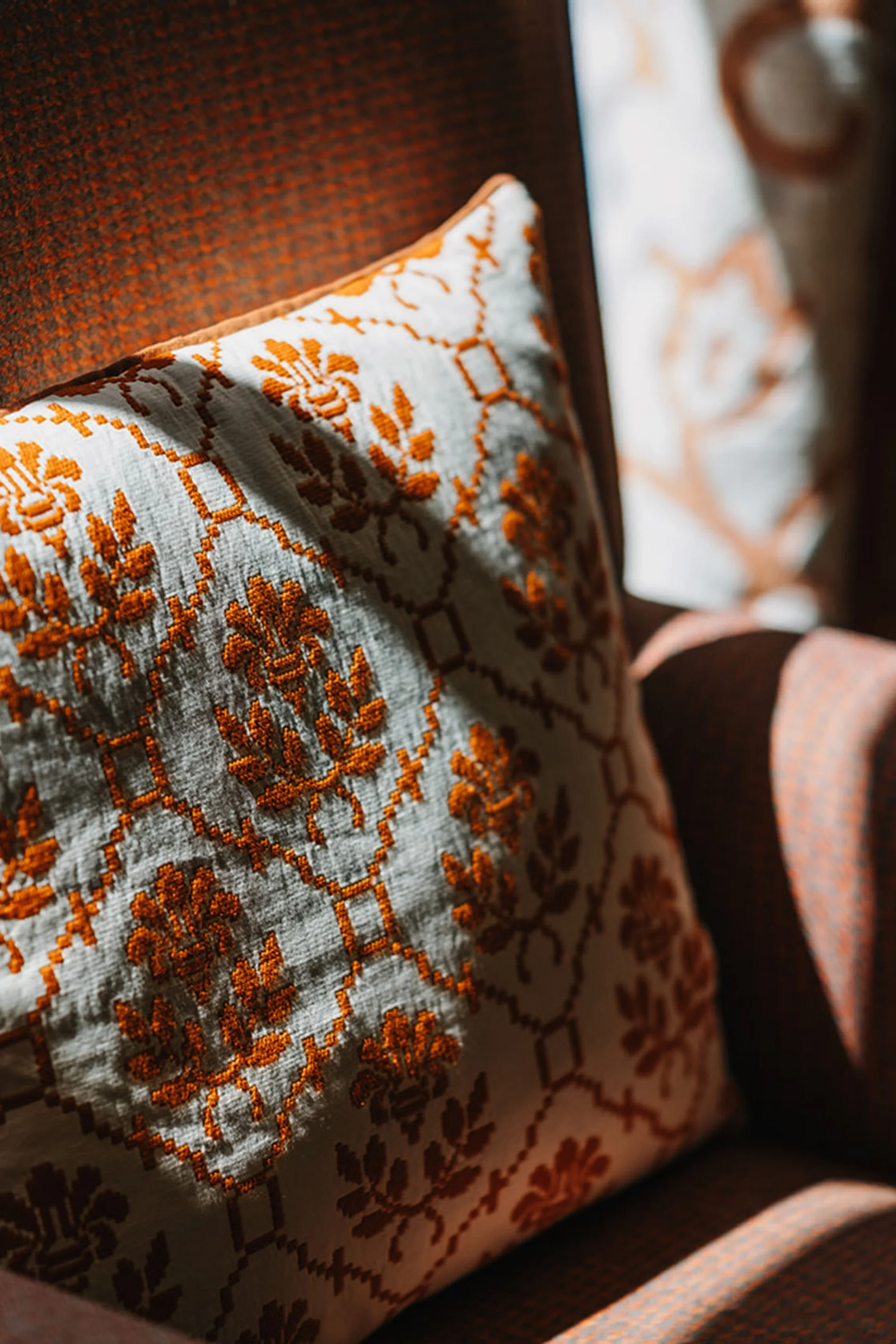 Aurora, Ihr Hotel in Lech am Arlberg Gemusterter Kissenbezug auf braunem Stuhl bei Sonnenlicht