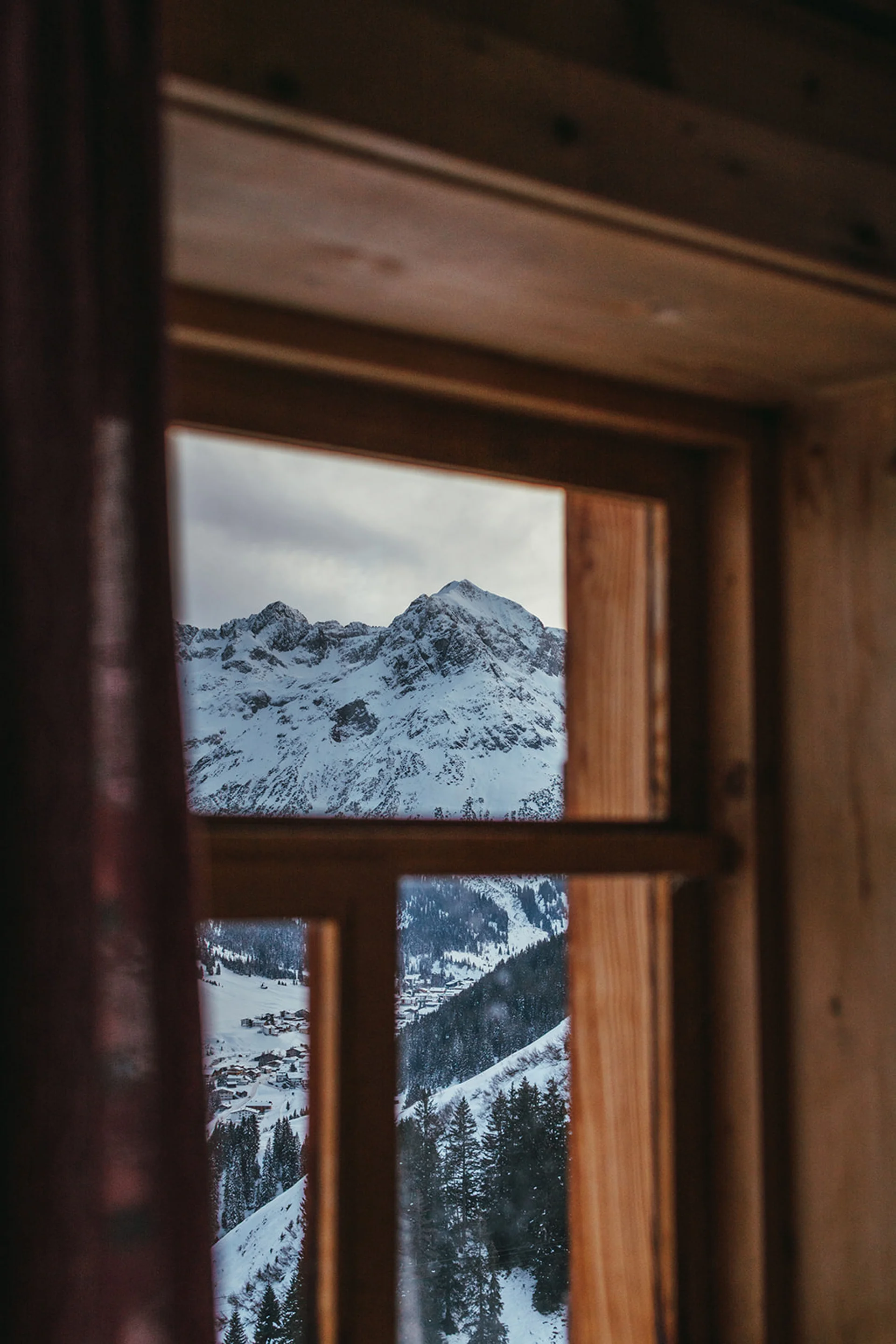 Aurora, Ihr Hotel in Lech am Arlberg Blick aus Holzfenster auf schneebedeckte Berge und Wälder
