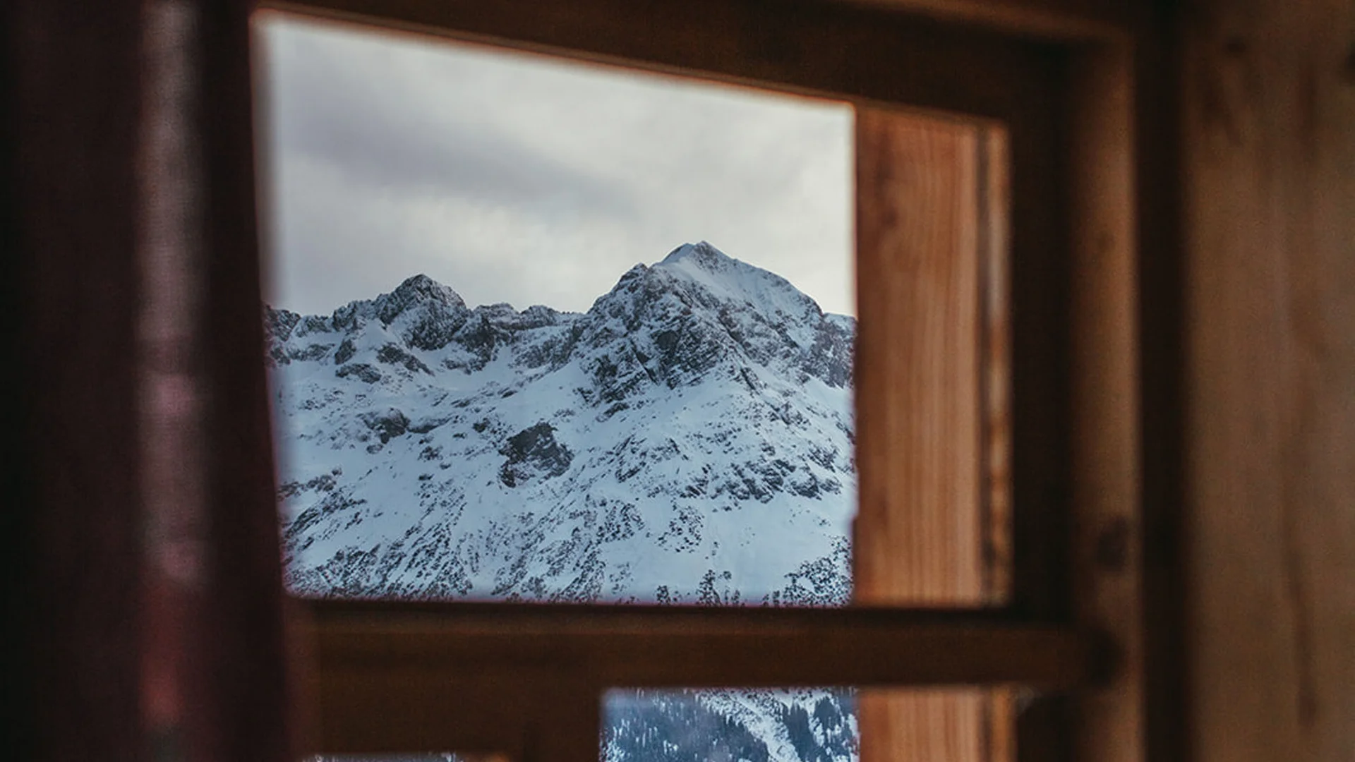 Aurora, Ihr Hotel in Lech am Arlberg Blick aus Holzfenster auf schneebedeckte Berge und Wälder