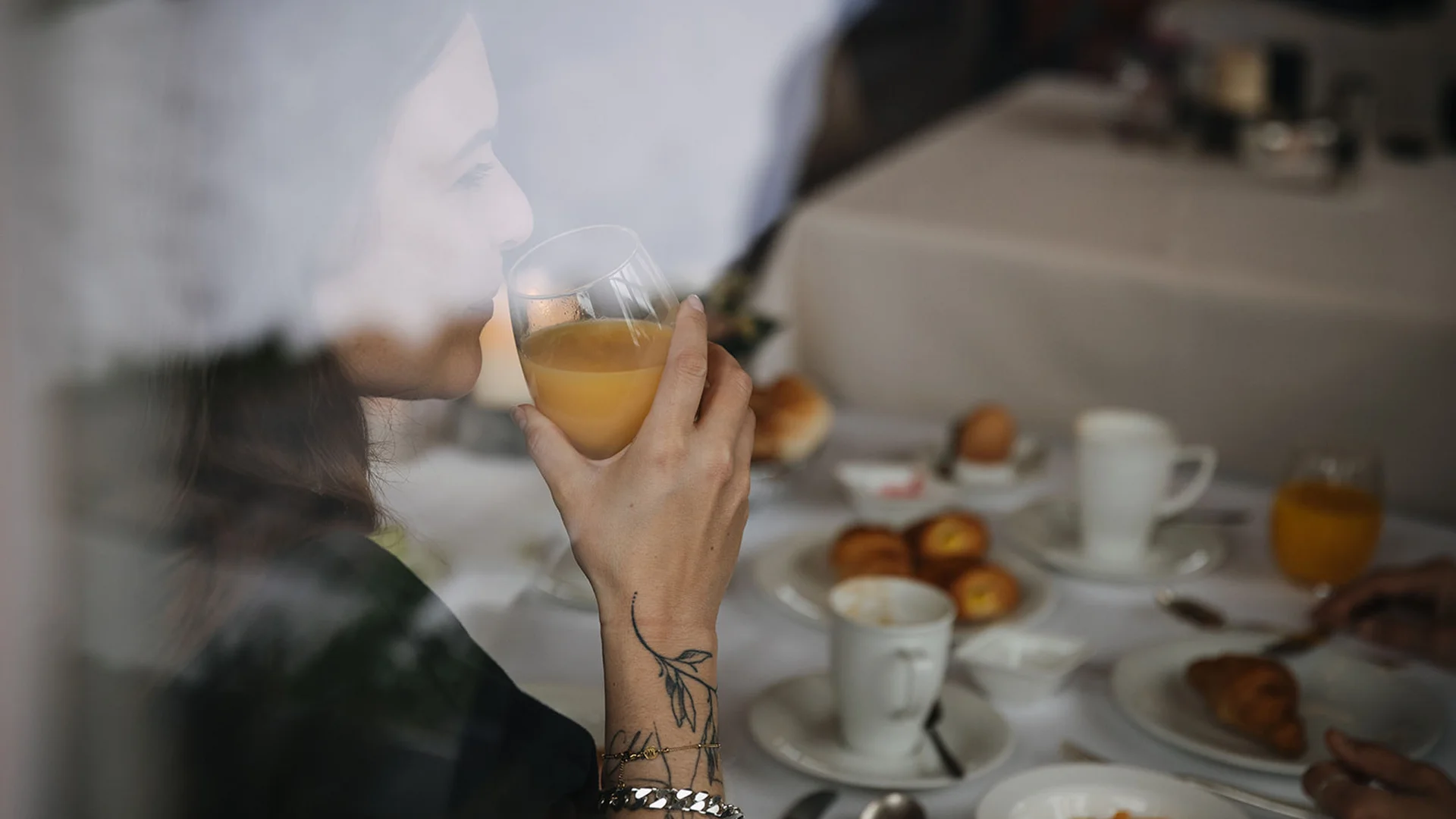Aurora, Ihr Hotel in Lech am Arlberg Frau trinkt Orangensaft beim Frühstück an einem gedeckten Tisch