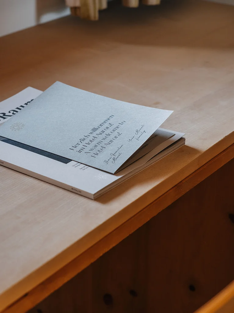 Aurora, Ihr Hotel in Lech am Arlberg Willkommensschreiben im Hotel Kurorai auf einem Holztisch