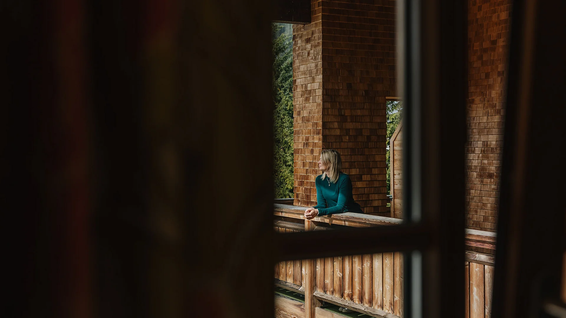 Aurora, Ihr Hotel in Lech am Arlberg Frau blickt von einem hölzernen Balkon in eine naturnahe Umgebung