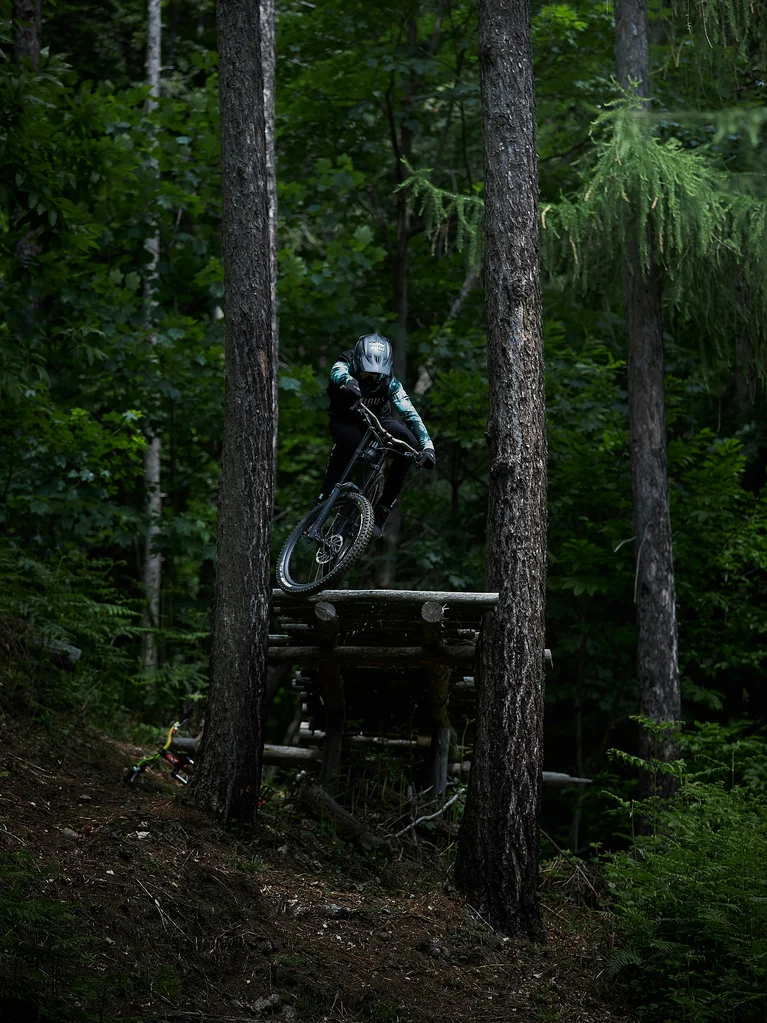 Culture and events in Lech am Arlberg Mountain biker jumping off wooden ramp in dark forest