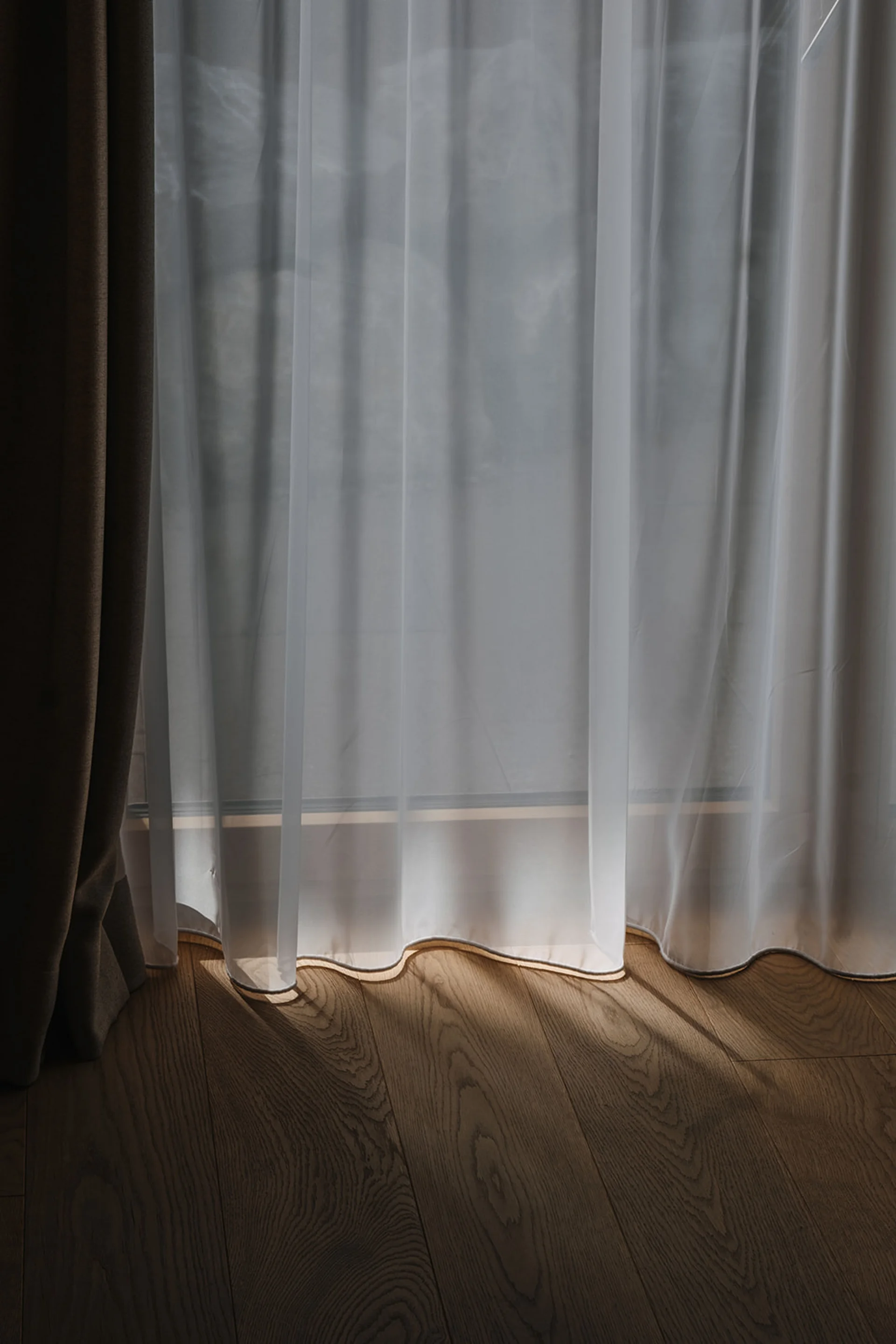 Aurora, Ihr Hotel in Lech am Arlberg Sonnenschein scheint durch einen weißen transparenten Vorhang auf einen hölzernen Boden