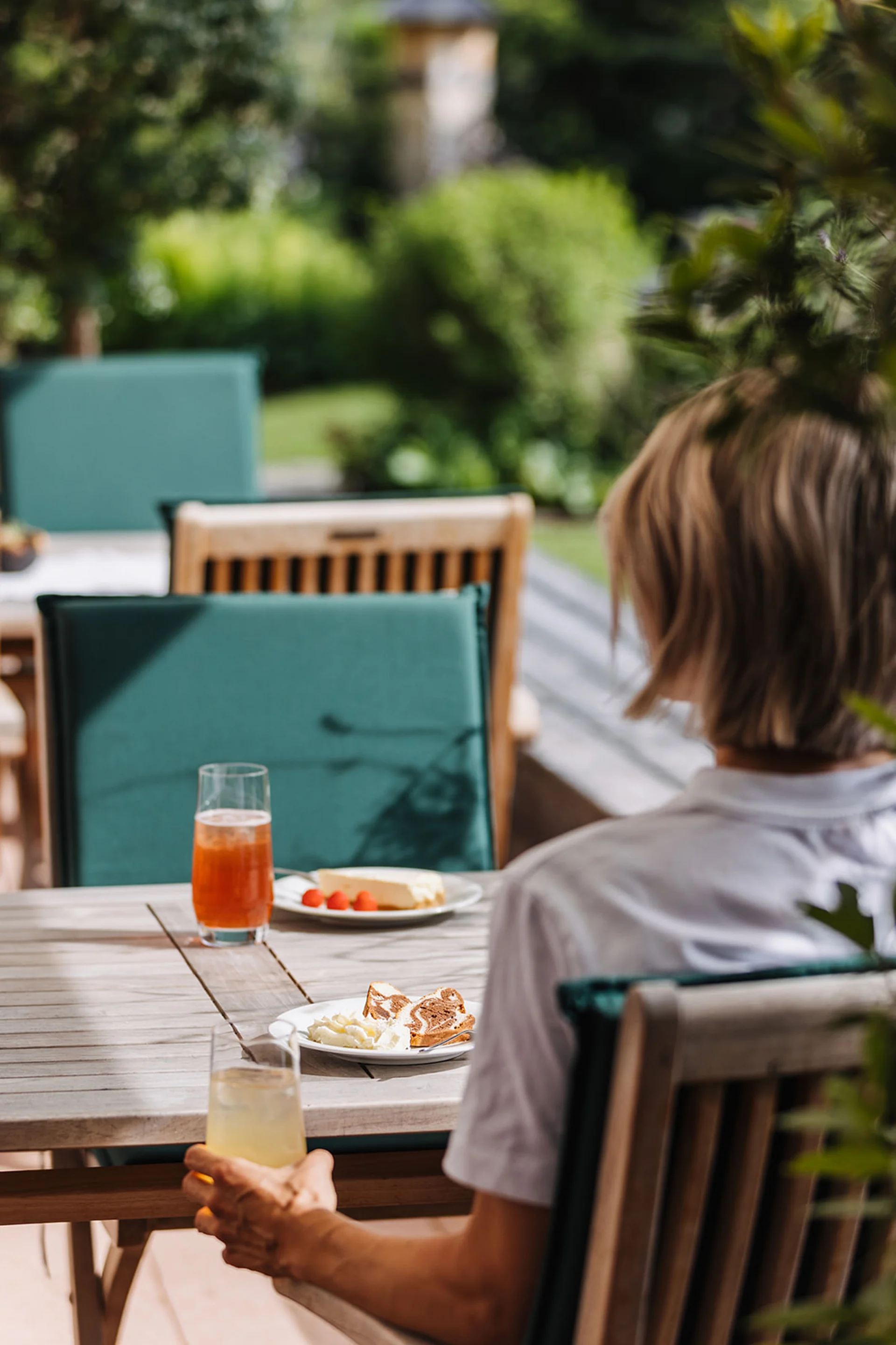 Aurora, Ihr Hotel in Lech am Arlberg Person sitzt draußen an Tisch mit Getränken und Snacks im Garten