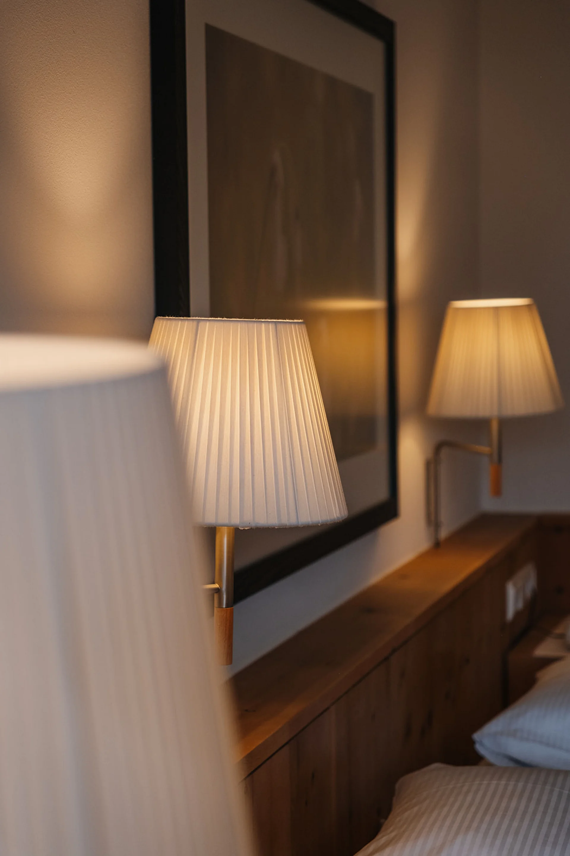 Aurora, Ihr Hotel in Lech am Arlberg Beleuchtete Wandlampen über einem hölzernen Bettrahmen in einem Schlafzimmer