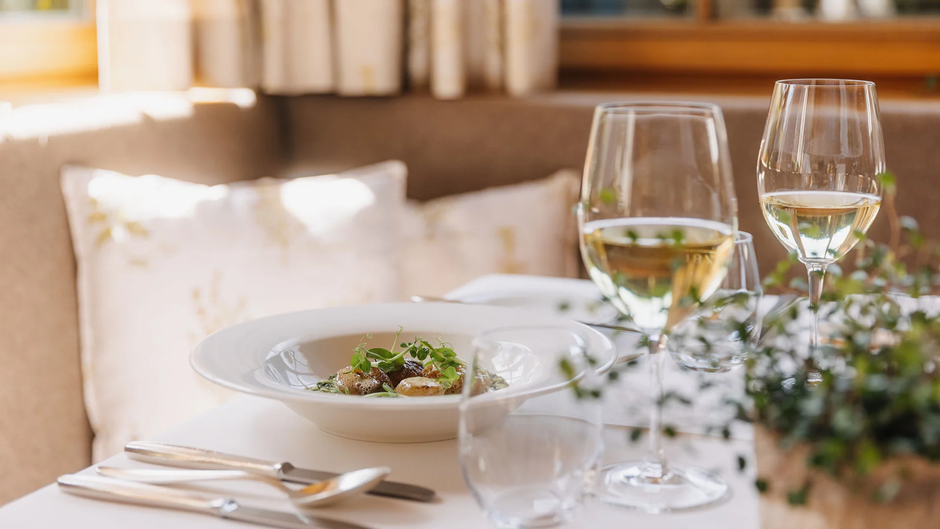 Aurora, Ihr Hotel in Lech am Arlberg Fein gedeckter Tisch mit Gourmetgericht und zwei Gläsern Weißwein