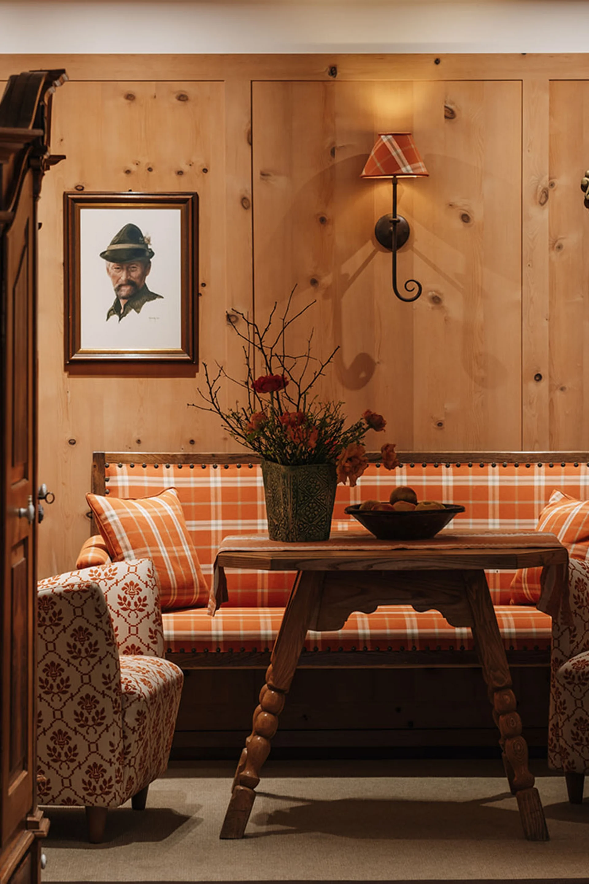 Aurora, Ihr Hotel in Lech am Arlberg Gemütliche Sitzecke mit Holzvertäfelung, karierten Polstern und Jagdtrophäen an der Wand